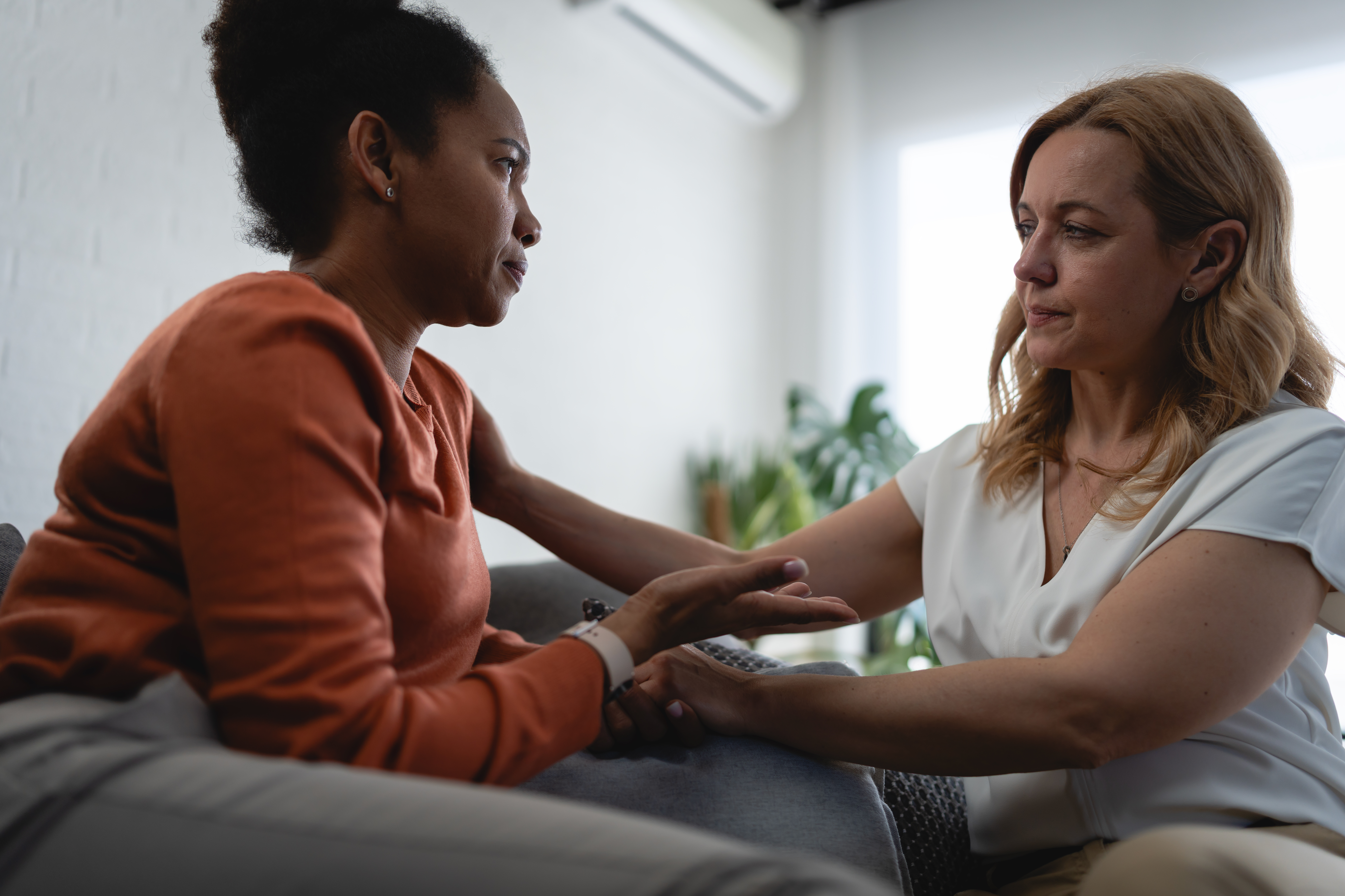 Upset woman is comforted by a therapist during an emotional counseling session, representing grief, loss, sadness and coping with difficult life experiences